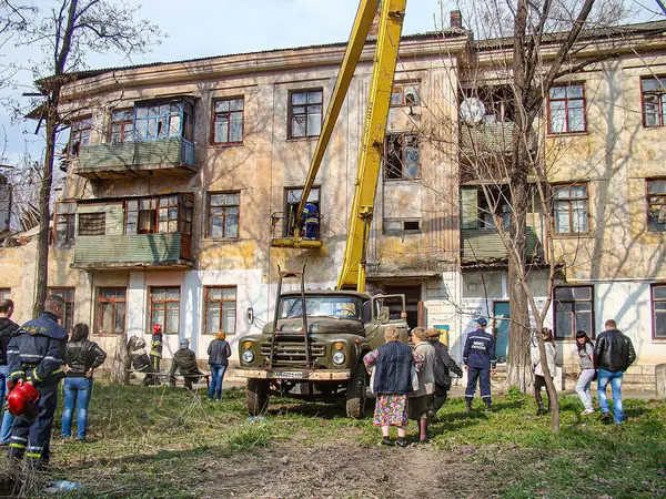 Görüntü, vinç ve işçilerin yer aldığı çok katlı bir binanın onarımlı veya bakımlı olduğu kentsel bir sahneyi gösteriyor. Binada görünür hasar belirtileri var, Tr Kostiantynivka, Ukrayna, 01-15-2013