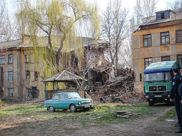 Hasarlı binaların, enkazların, park halindeki bir arabanın ve yakınlarda duran bir kişinin olduğu felaket sahnesinin görüntüsü. Arka planda kısmen gizlenmiş bir kamyon, Kostiantynivka, Ukrayna, 01-15-2013