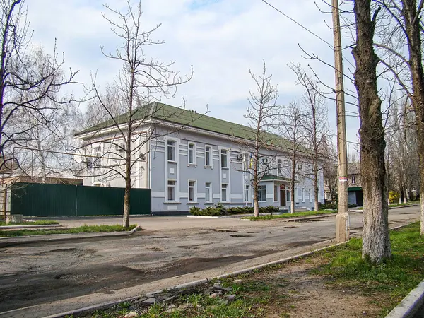 İki katlı, pencereleri, balkon verandaları ve bacası olan beyaz bir apartman. Arazinin garaj ya da avlusu var, yaprakları olmayan ağaçlar, Kostiantynivka, Ukrayna, 01-15-2013