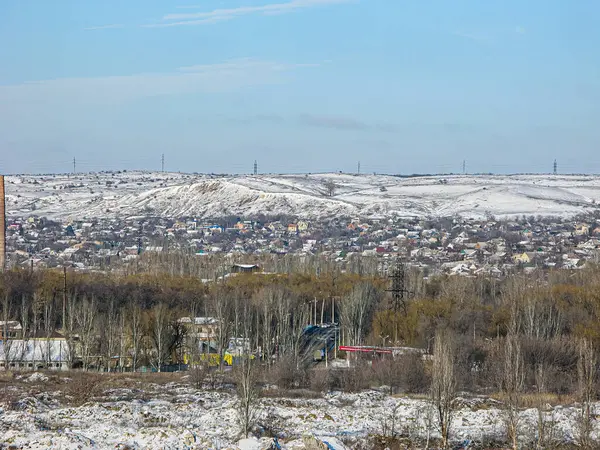 Karla kaplı bir kış manzarası, çıplak ağaçlar, evler, tepeler veya alçak dağlar, bulutlu gökyüzü Kostiantynivka, Ukrayna, 01-15-2013