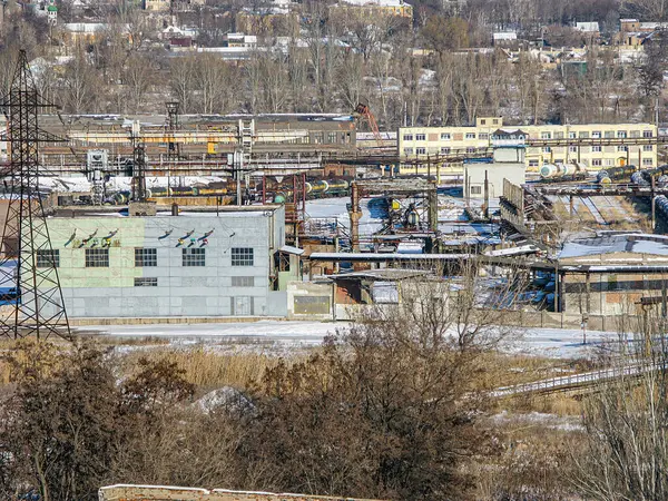 Görüntü, Kostiantynivka, Ukrayna, 01-15-2013 sahnesinde, kentsel bir bölgedeki diğer bina ve depolarla çevrili, birden fazla bölüm ve makineye sahip, karla kaplı büyük bir endüstriyel kompleksi gösteriyor.