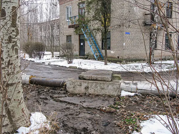 Görüntü, bozulma, kısmen tıkanmış yol, kar ve çamur, soyulmuş boya ve yıpranmış cepheli eski binalar, eğilmiş ağaç, üstten Kostiantynivka, Ukrayna, 01-15-2013