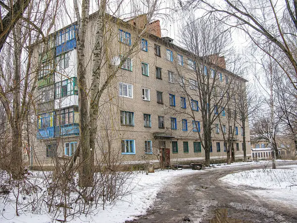 Görüntü, Orta veya Doğu Avrupa 'da daha soğuk aylarda Kostiantynivka, Ukrayna, 01-15-2013 döneminde tuğla işi, sayısız pencere, beyaz çerçeve ve mavi panjurlu çok katlı bir konut gösteriyor.