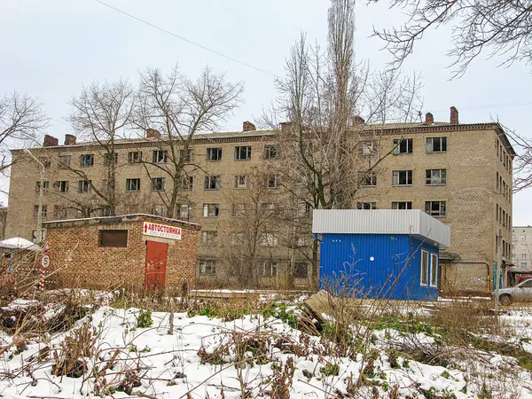 Çok katlı yıpranmış bir bina ve mavi bir inşaat karavanı olan şehir kış manzarası. Bölge boş, ne insan ne bitki örtüsü, ne Kostiantynivka, Ukrayna, 01-15-2013