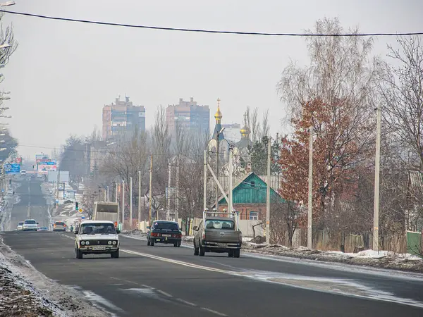 Görüntü, hareket halindeki araba ve kamyonlarla Doğu Avrupa banliyölerinde karlı bir yol gösteriyor. Mimari yapı, Kostiantynivka, Ukrayna, 01-15-2013 tarihli bir kilise de dahil olmak üzere bölgeyi gösteriyor.