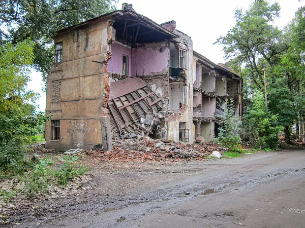 Terk edilmiş, harap olmuş, camları kırık ve aşırı gelişmiş bir alanda hasar görmüş bir bina. Çevredeki yol Kostiantynivka, Ukrayna, 06-15-2013