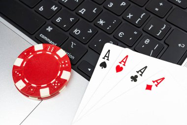 Görüntü, kumar, sanal kumarhane oyunları, finansal işlemler ve rakamları içeren online oyun veya evden çalışma senaryolarını ima eden, çipler, kartlar ve olası bir laptop içeren bir poker düzeneği gösteriyor.