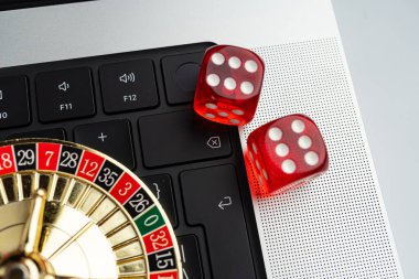 Görüntü, bilgisayar klavyesinde kumarhane zarları ve rulet tekerleklerini gösteriyor. Dijital teknoloji ya da elektronik oyun temalı kumar temasını ima ediyor.