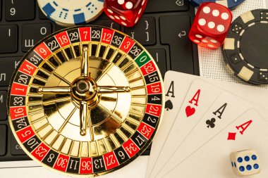 Oyun, kumar, eğlence ve finans piyasalarıyla ilişkili risk alma temalı dizüstü bilgisayarlı masa başında rulet tekerleği, kart ve zar içeren bir kumarhane görüntüsü