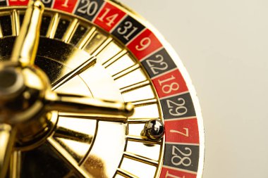 Kırmızı ve siyah kompartımanlarla hızlanan bir altın rulet tekerleğinin yakın çekimi kumarhanelerde şans, şans ve heyecan temalarını çağrıştırıyor.