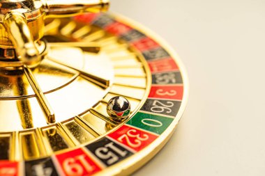 Bir dönen rulet tekerleği görüntüsü, altın çember ve renkli numaralandırılmış slot makineleri üzerine odaklan kumar kültürünün yüksek kalitede tasviri, heyecan uyandıran bulanık efektler.