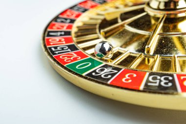 Görüntü, bulanık metal bir top, kırmızı ve siyah numaralandırılmış bahis alanları, yeşil 0 cep, beyaz işaretli ek bahis seçenekleri ile donatılmış bir rulet çarkı içeriyor.