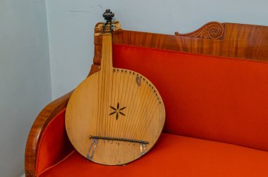 Süslü, ahşap bir yatağa yaslanmış, müzikal çağrışımlı, rahat, nostaljik bir atmosfer öneren, klasik bir gitar.