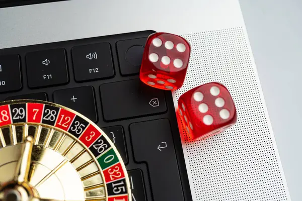 Görüntü, bilgisayar klavyesinde kumarhane zarları ve rulet tekerleklerini gösteriyor. Dijital teknoloji ya da elektronik oyun temalı kumar temasını ima ediyor.