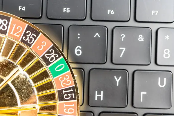 Bir dönen rulet çarkı bulanık bir bilgisayar klavyesine karşı 0 'a iniyor. Kumar, şans ve online oyun temaları öneriliyor.