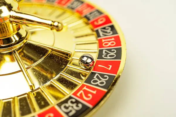 Kırmızı ve siyah sayılarla dönen bir altın rulet çarkı, hareket halindeki gümüş top heyecan ve kumar beklentisini yakalar.