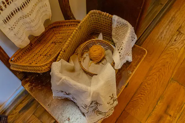 Görüntü, ahşap bir zeminde dantel altlık içeren bir sepetle bir iç tasarım teması tasvir ediyor. Zarafet, klasik cazibe, ev konforu ve pazarlama fu 'sunda kullanılan sıcaklığı çağrıştırıyor.