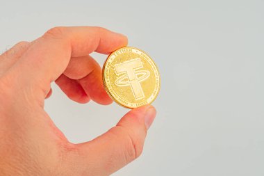 Bir el, dijital varlıkları, engelleme zinciri teknolojisini ve finansal yenilikleri sembolize eden bir altın testereli para gösteriyor.