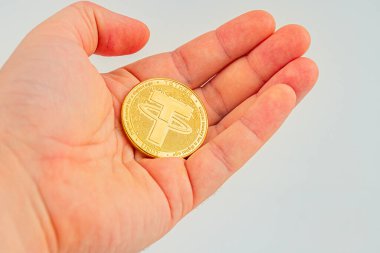 Görüntü, kripto para bağını sembolize eden, elinde para jetonu tutan bir kişiyi tasvir ediyor.