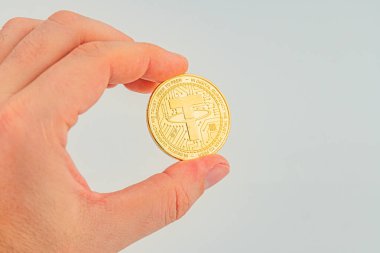 Dijital finansman teliyle ilişkili şifreli para ya da koleksiyon ürünü sembolize eden, madeni para tutan bir kişinin yakın plan görüntüsü