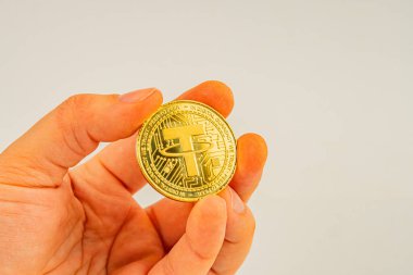 Görüntü, kripto para tanıtımı, yatırım reklamı veya eğitici para bağlama için kullanılan sade bir zemine karşı insan eli tarafından tutulan değerli metal gibi karmaşık bir şekilde tasarlanmış fiziksel bir bağlayıcı madeni para tasvir eder.