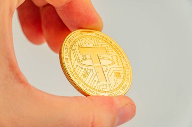 Altın renkli bir para bağını tutan bir elin görüntüsü, kripto para birimini sembolize ediyor. Tasarım dijital para piyasasındaki değeri ve statüsünü ima ediyor.