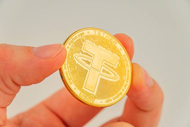 Bir el, üzerinde atomik oymalar ve kripto para değerleriyle ilgili yazı olan bir altın bağlayıcı para jetonu tutar.