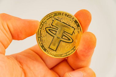 Bir el, Bitcoin logo testereli altın bir sikke gösteriyor.