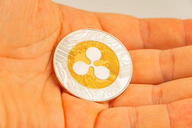 Yüzünde Bitcoin sembolü bulunan ve muhtemelen dijital varlıklar için bir koleksiyon ya da promosyon unsurunu temsil eden fiziksel bir madeni para jetonunu tutan bir elin yakın plan resmi.