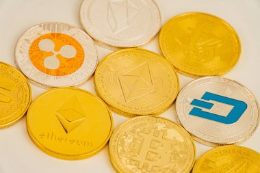 Bitcoin, Ethereum, Litecoin ve Dash gibi çeşitli dijital para birimlerinin logolarına saçılmış altın renkli para koleksiyonu.