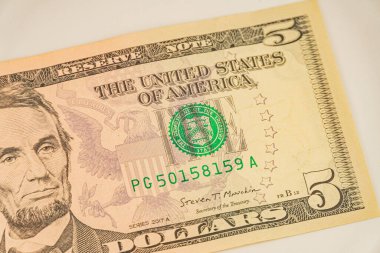 Abraham Lincoln 'ün portresini, seri numaralarını ve Federal Rezerv Bölgesi mührünü vurgulayan iki ABD 5 banknotunun yakın plan görüntüsü, yüzgeç için ABD para biriminde güvenlik tedbirleri ve tasarım unsurlarını tartıştı