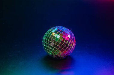 Bir disko topunun yakın çekimi, etrafındaki ışıklardan dolayı birden fazla rengi yansıtıyor, canlı ve dinamik dans ortamını çağrıştırıyor