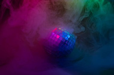 Girdap içindeki dumanın ortasındaki bir disko topunun görüntüsü, canlı bir atmosferde birden fazla rengi yansıtan, retro disko kültürünü anımsatan