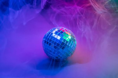 Canlı, renkli dumanların içinde bir disko topunun görüntüsü partiler ve eğlence mekanları için şenlikli duygular uyandırıyor.