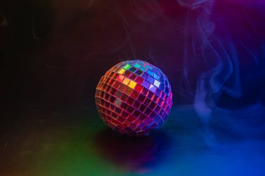 Canlı, aydınlık bir disko topu dumanlı bir partiye ya da gece kulübüne yansıyor.