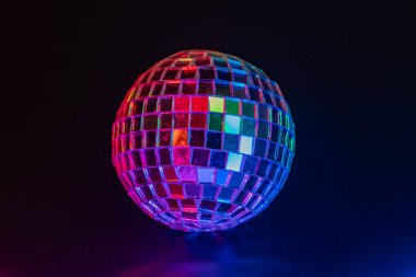 Işıldayan disko topu renkli ışıkları yansıtıyor, canlı bir dans partisi havası yaratıyor.
