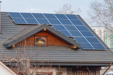 Görüntü, sürdürülebilir yaşam ve enerji korumasını sembolize eden, güneş panelleri olan, modern, çevre dostu bir ev tasvir ediyor.