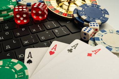 Canlı bir görüntü çevrimiçi oyun, poker kartlarının ve geleneksel kumarhane eşyalarının sergilendiği dizüstü bilgisayar ekranı klasik kumar unsurlarının birleşimini sembolize ediyor.