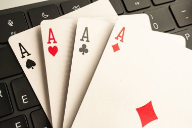 Resim, bir bilgisayar klavyesi önünde, teknoloji, oyun veya stratejiyle ilgili temaları sembolize eden, bir iskambil destesinden dört as gösterir
