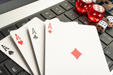 Görüntü poker çiplerini gösteriyor, Maça Ası 'na vurgu yapıyor, arka planda bir dizüstü bilgisayar, dijital bağlamda oyun veya kumar faaliyetlerini öneriyor