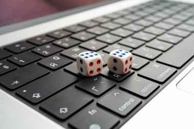 Dizüstü bilgisayarın klavyesinde iki zar bulunan bir fotoğraf, şans, teknoloji, karar verme ve dijital çevre konseptleri temaları arasında iş girişimleri, online kumar ve rand yer alabilir.