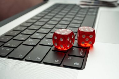 Bir dizüstü bilgisayarın klavyesindeki iki kırmızı zar, şans ve teknoloji arasındaki etkileşimi vurguluyor.