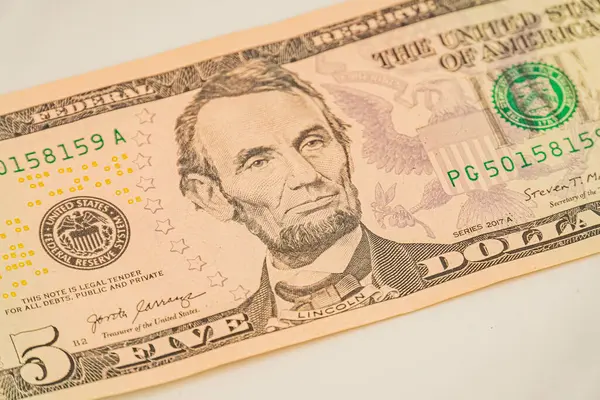 Abraham Lincoln profilli ve filigran 5, ABD 'li beş dolarlık bir banknotun resmi. Yasa bir yüzeye yerleştirilmiş, ancak ayarı ya da durumu bu açıdan belirsiz.