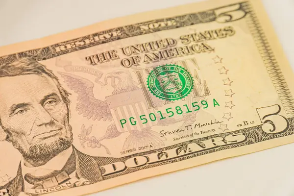 Abraham Lincoln 'ün portresi olan beş dolarlık banknotun yakın çekim, yüksek çözünürlüklü görüntüsü, kalpazanlıkla mücadele için filigran detayları ve güvenlik özellikleri sergileniyor