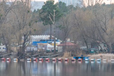 Renkli teknelerle sakin rıhtım manzarası, sakin su yansıtan ağaçlar ve binalar, yemyeşil alan, gevşeme ve doğayla bağlantı, seyahat için uygun, Kyiv, Ukrayna, 09-15-2024