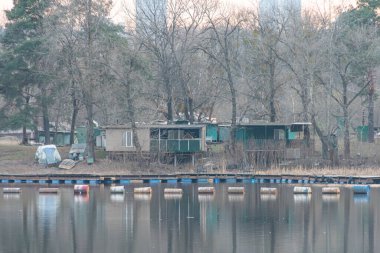 Ahşap rıhtım, mavi şamandıralar, kayıkhaneler, yeşillikler, ağaçlar ve balıkçılık ya da eko-turizm Kyiv, Ukrayna, 09-15-2024 gibi su faaliyetleriyle sakin bir göl manzarası