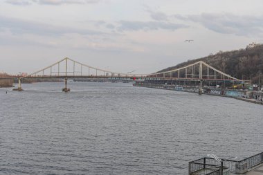 Geniş bir su kütlesi, hafif dalgalar, kentsel liman bölgesi, modern köprü ve potansiyel eğlence faaliyetlerine sahip sakin bir marina sahnesi huzur, huzur, tra Kyiv, Ukrayna, 09-15-2024