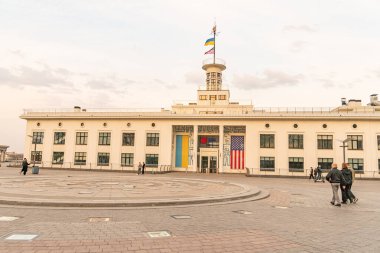 Bayraklı büyük, beyaz bir bina, muhtemelen bir hükümet veya eğitim kurumu, dairesel bir garaj yolu ve çevrede yürüyen insanlar, ayarı int Kyiv, Ukrayna, 09-15-2024