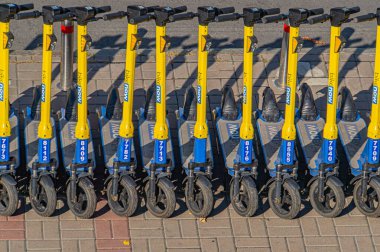 Modern bir ortamda sarı ve mavi renkli elektrikli scooterların temiz ve organize bir gösterisi, yenilik, rahatlık ve çevre dostu Kyiv, Ukrayna, 09-15-2024