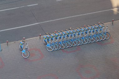 Şehir sakinleri ve ulaşım arayan ziyaretçiler için kaldırıma dizilmiş birden fazla mavi bisikletli bir bisiklet paylaşım istasyonu. Ayarlar I Kyiv, Ukrayna, 09-15-2024